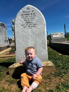 The youngest Arthur Bush in front of the original Arthur's headstone